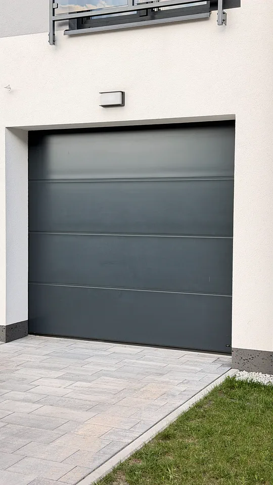 Antracytowa brama garażowa segmentowa przy podjeździe z kostki — realizacja EASY OPEN